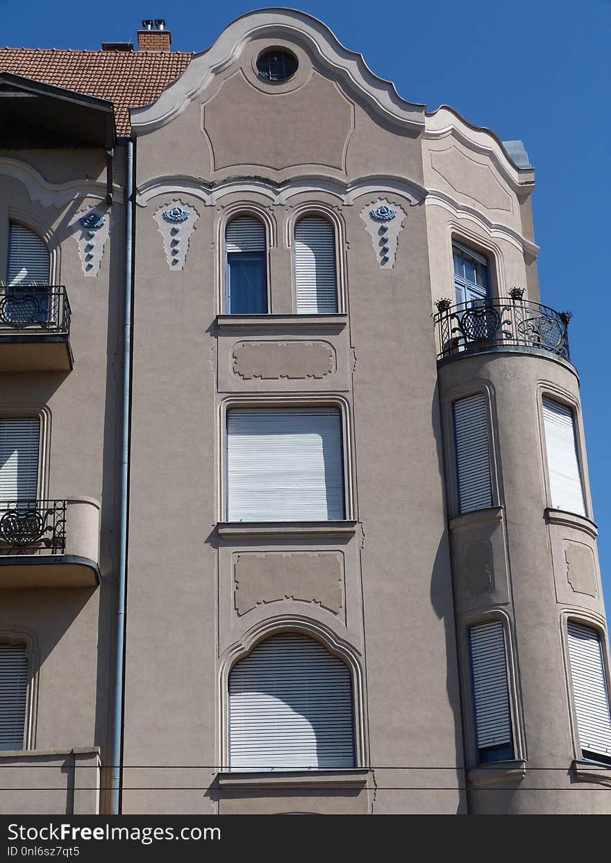 Secessionist style facade detail with balcony and white windows, ceramic decorations under blue sky