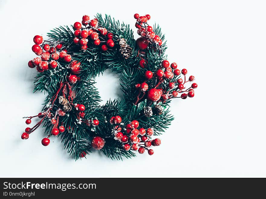 Christmas decorative wreath of holly, ivy, mistletoe, cedar and leyland leaf sprigs with red berries over white background.