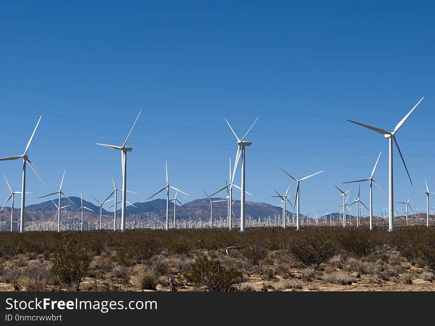 Wind mills working on hills with blue sky on background