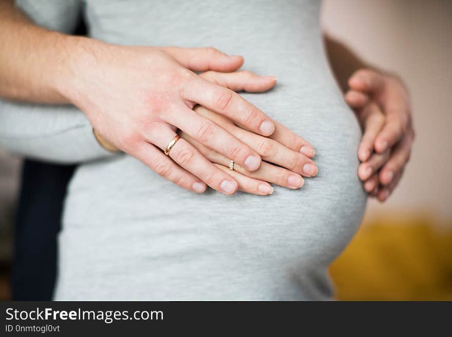 Close Up Of Male And Female Hands Resting On Pregnant Womans Stomach