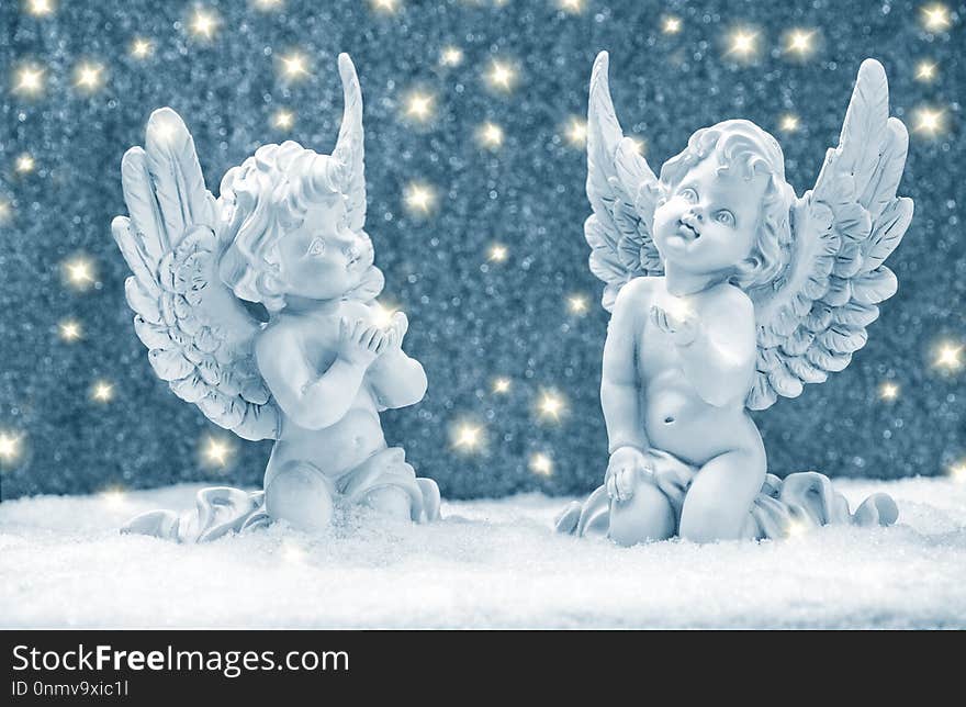 Little guardian angels in snow with golden lights. Christmas decoration