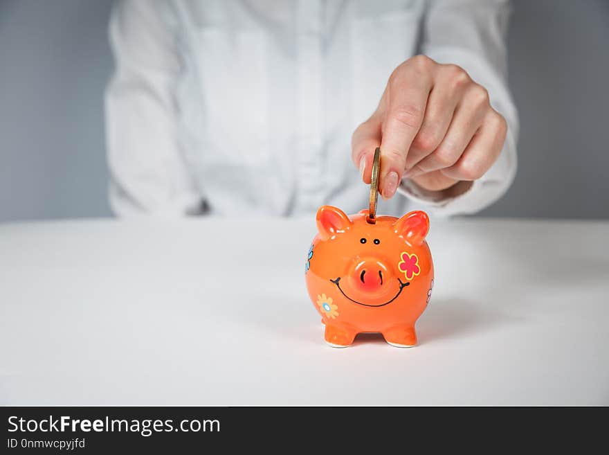 Savings, money, annuity insurance, retirement and people concept - close up of senior woman hand putting coin into piggy bank