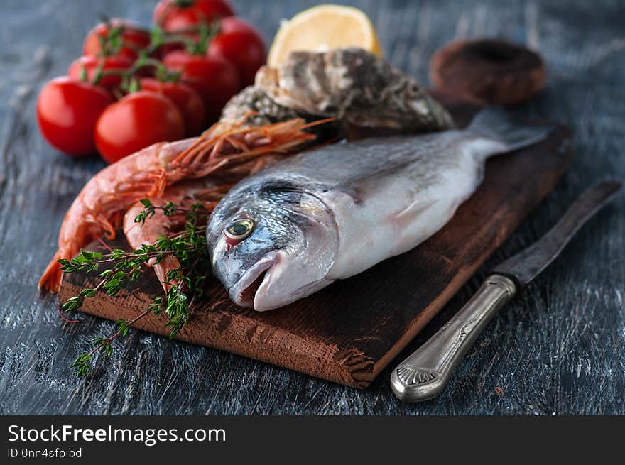 Fresh sea fish dorado with oysters and shrimp and vegetables. Delivered on a dark base