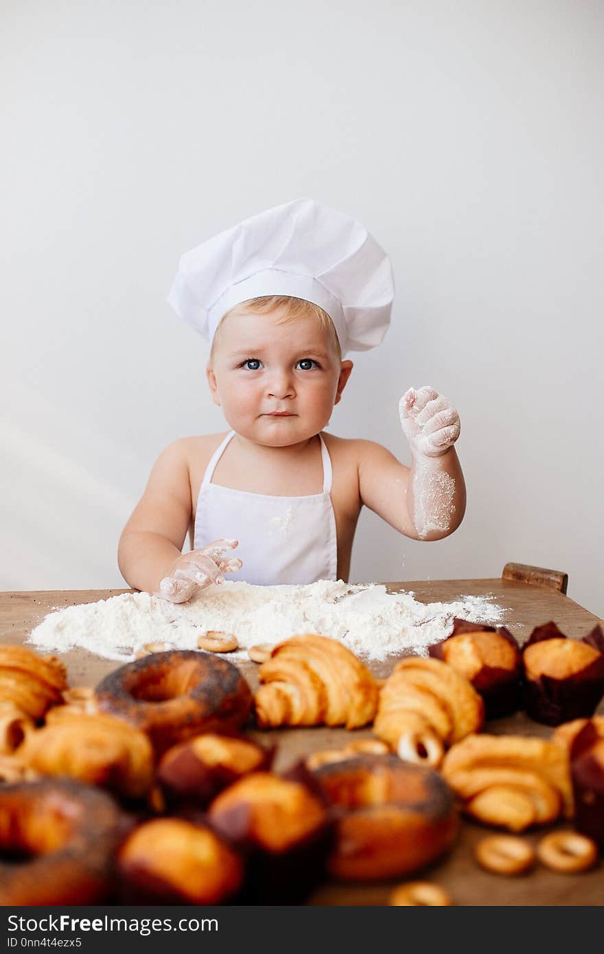 A little boy in a chef`s suit with flour and rolls. A little boy in a chef`s suit with flour and rolls.