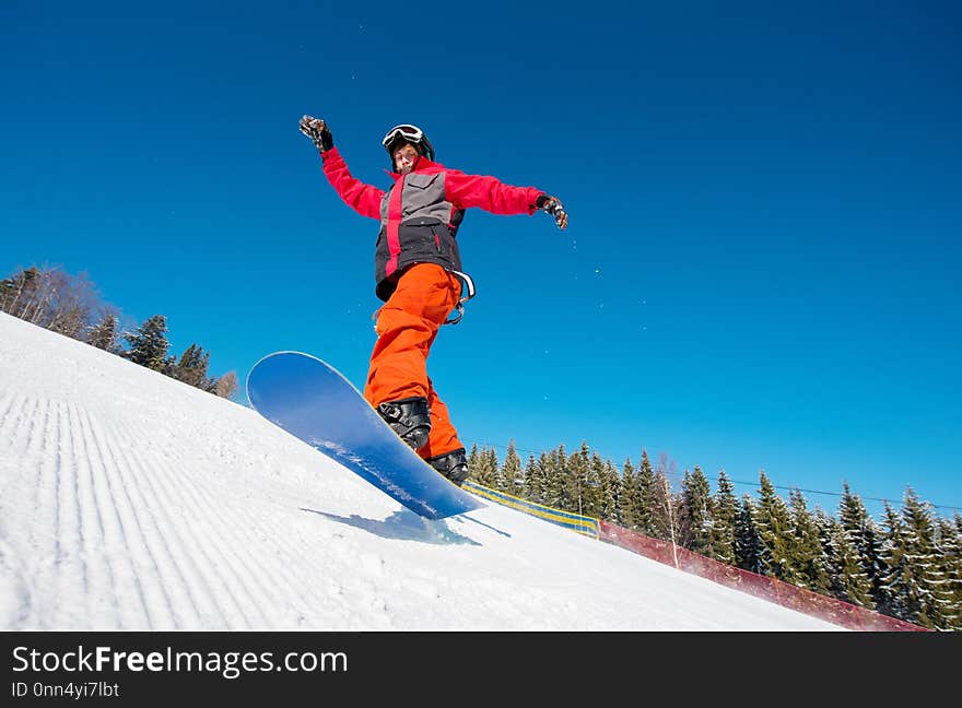 Snowboarder in the air while riding on the slope in the mountains on a beautiful sunny winter day. Blue sky on the background active lifestyle sports concept