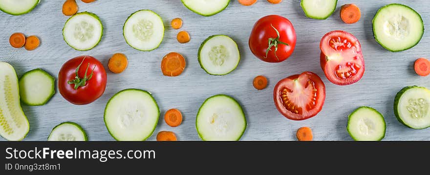 Wide photo vegetables on wooden background. Top view of cucumbers, tomatoes, zucchini, carrots