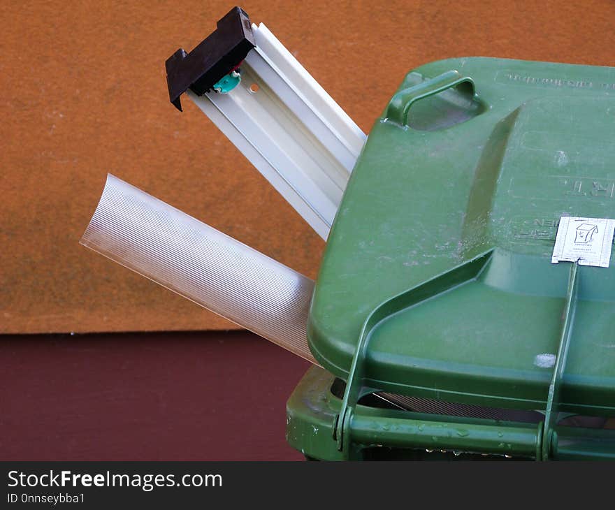 Green plastic recycling bin with recycled items sticking out