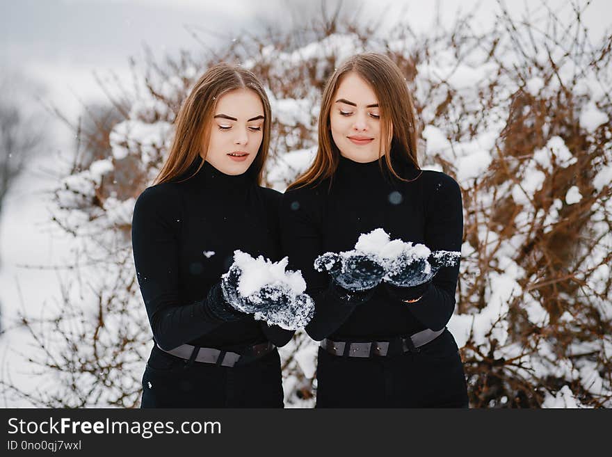 Cute girls walking in a winter park. Sisters have fun with snow. Cute girls walking in a winter park. Sisters have fun with snow