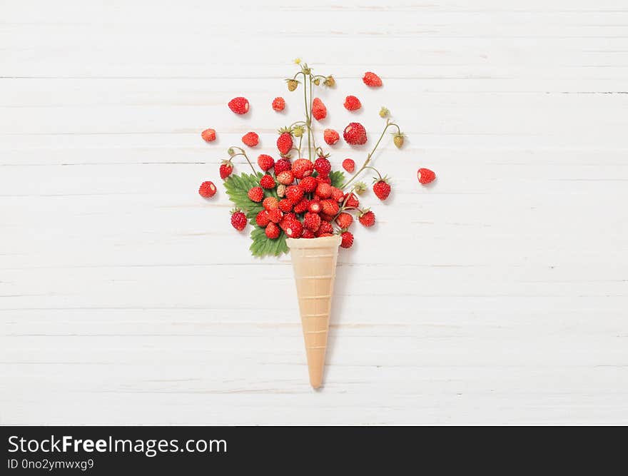 Waffle cone with strawberries on wooden background