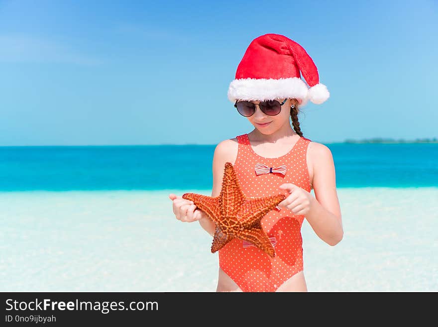 Little girl in Christmas hat on white beach during Xmas vacation. Little girl in Christmas hat on white beach during Xmas vacation