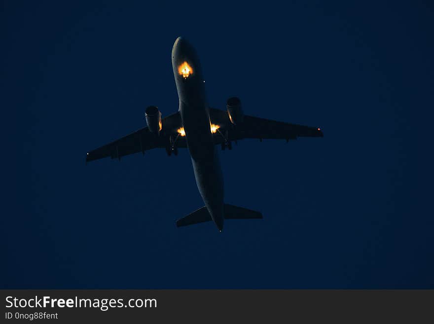 Airplane in the sky at sunset with landing lights on