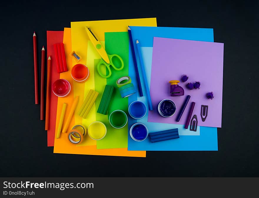 School accessories are laid out in the form of a rainbow. Black background.Happy back to school student. Art and crafts for kids. Child learning rainbow colors, alphabet letters and numbers