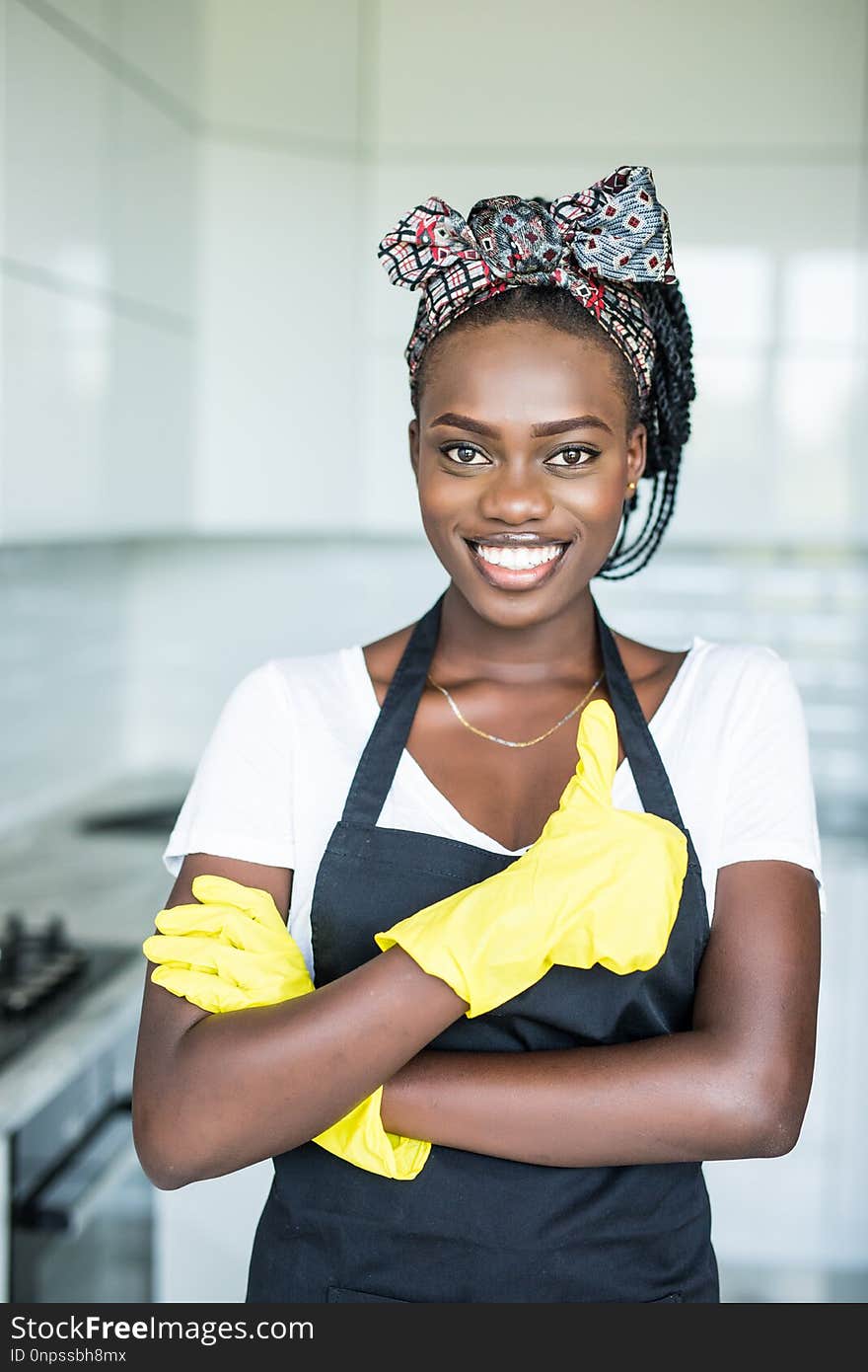 Young african woman in yellow gloves who showing thumb up in the room