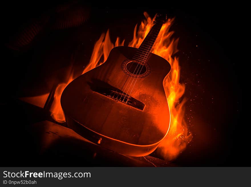 Music concept. Acoustic guitar on a dark background under beam of light with smoke with copy space. Exploding guitar. Fire effects. Surreal guitar. Selective focus. Music concept. Acoustic guitar on a dark background under beam of light with smoke with copy space. Exploding guitar. Fire effects. Surreal guitar. Selective focus