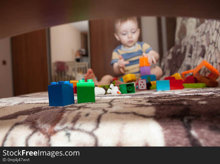 Sweet little boy building tower from cubes at home.