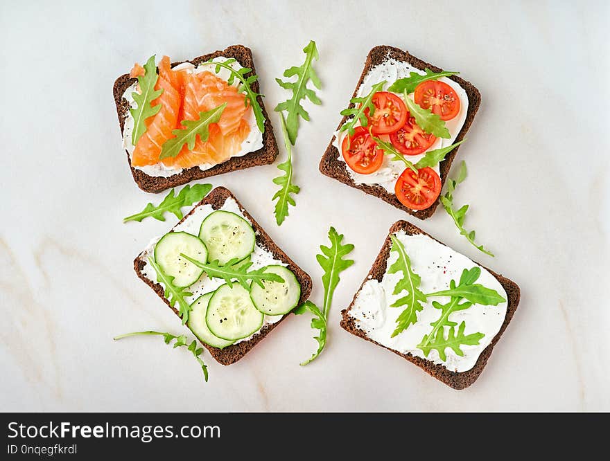 Smorrebrod - traditional Danish sandwiches. Black rye bread with salmon, cream cheese, cucumber, tomatoes on wooden background