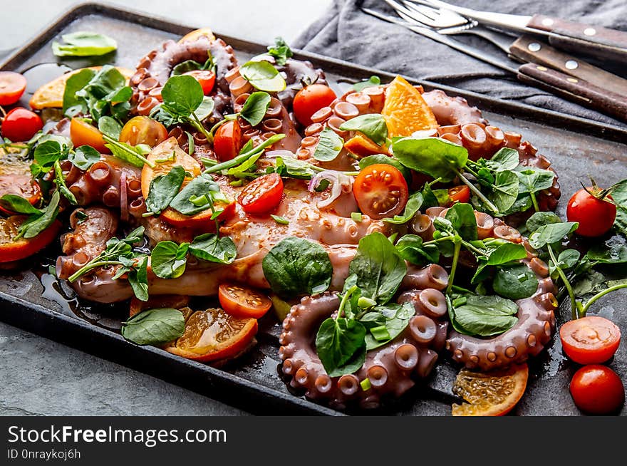 Whole octopus salad with orange, tomatoes and cress salad served on board with wine.