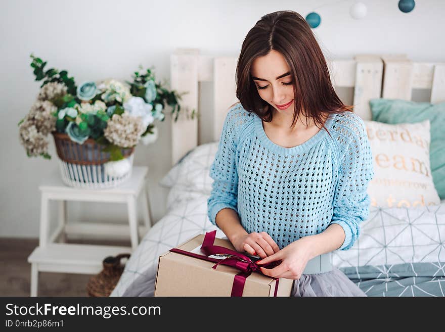 Happy smiling girl sitting in bed with present box