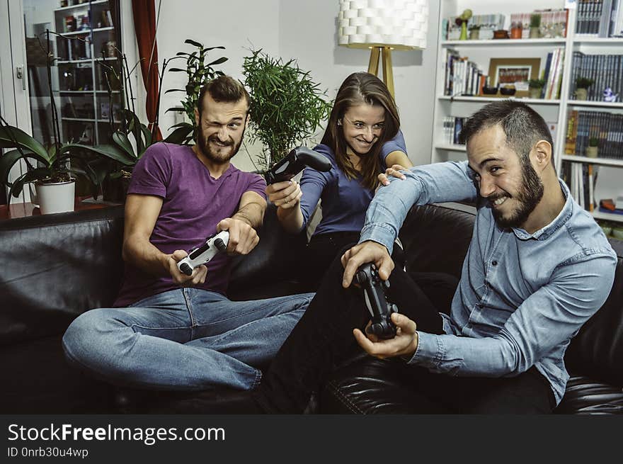 Happy excited friends playing video games at home together and having fun