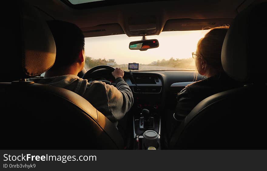 A married couple travels by car, the setting sun illuminates them. Asian man driving