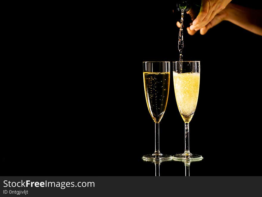 Two glasses with champagne pouring from bottle ready to toast in Celebration concept at New Years eve Christmas Valentines day and happy times isolated on black background copy space and studio light. Two glasses with champagne pouring from bottle ready to toast in Celebration concept at New Years eve Christmas Valentines day and happy times isolated on black background copy space and studio light