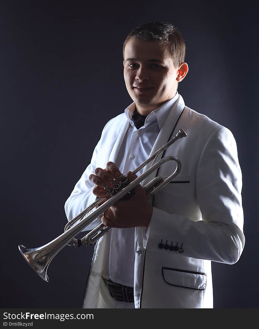 Young man in a white suit with a trumpet.isolated on black background.