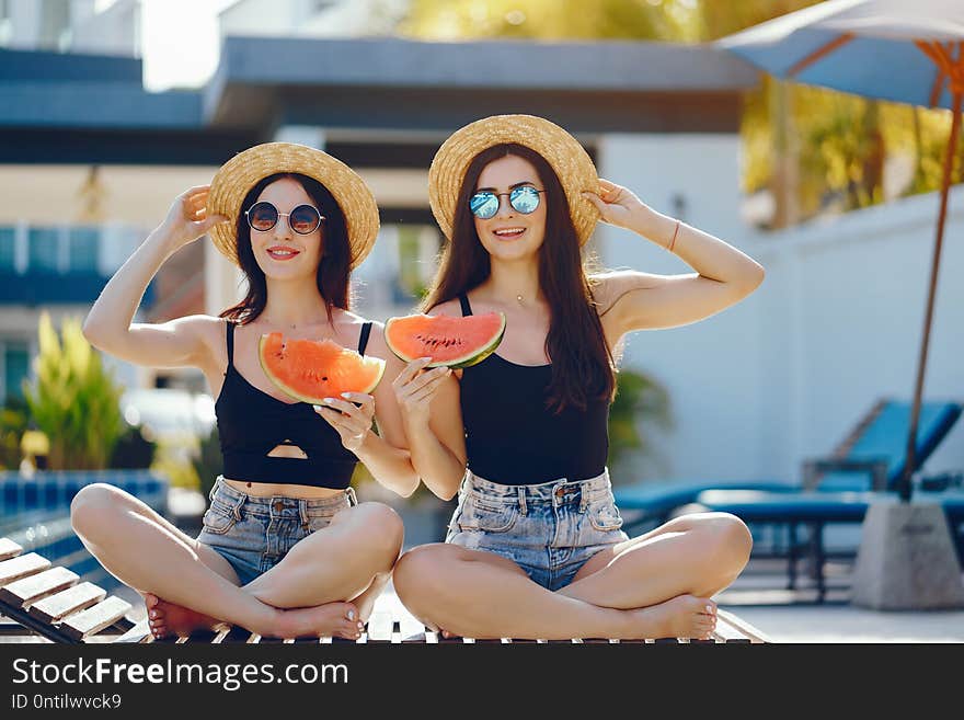 Two girls eating watermelon by the pool in Thailand