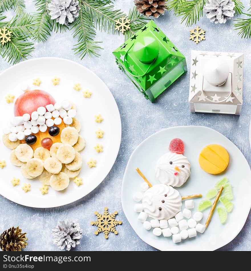 Christmas food for children - kiwi Christmas tree, marshmallow snowman, banana Santa Claus. Top view