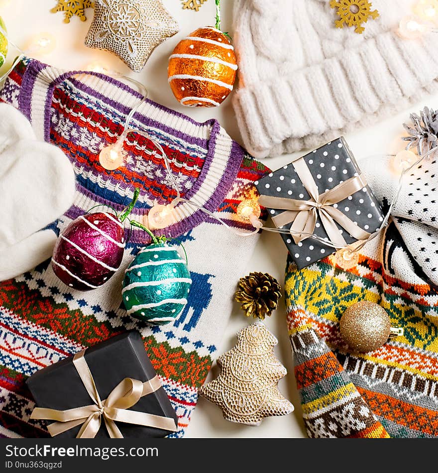 Christmas mood composition with Christmas sweater, hat, presents and lights. Winter concept flat lay, top view