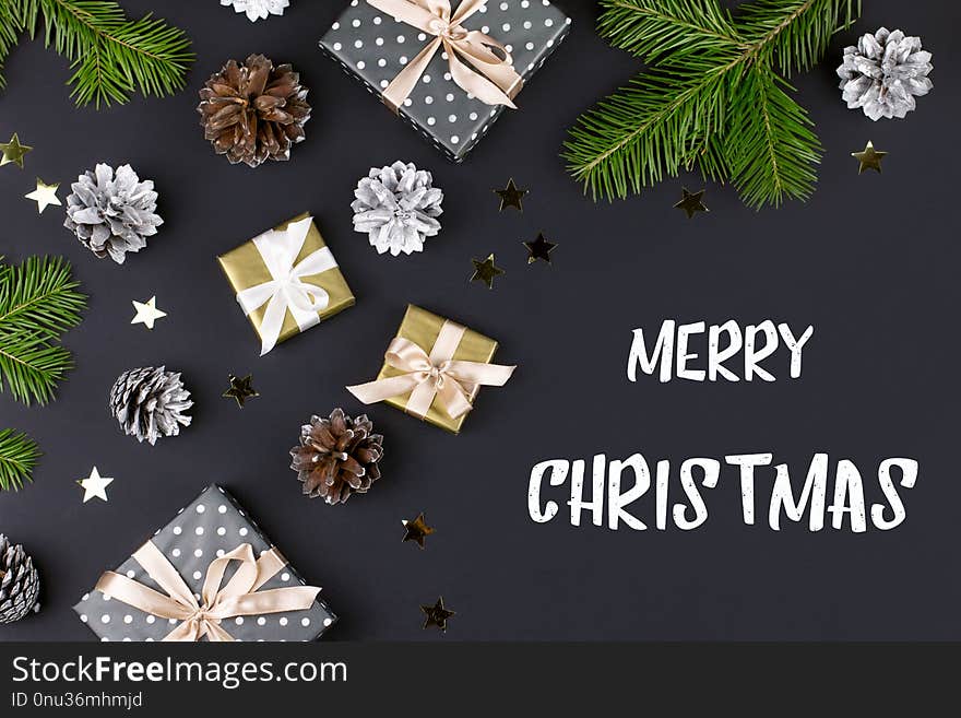 Merry Christmas and Happy New Year greeting card with fir branches, presents, decorations on black