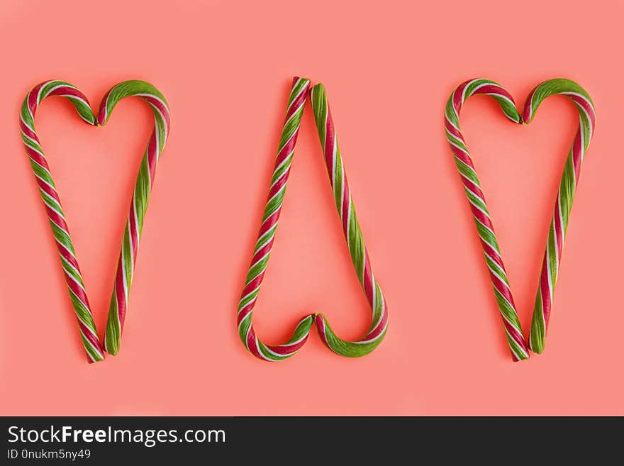 Christmas candy canes shaped heart on coral background. Color of the 2019 year