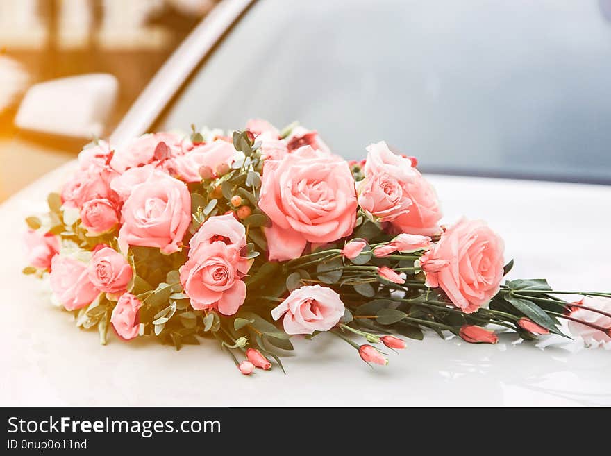 Beautiful wedding bouquet of roses on the hood of a car