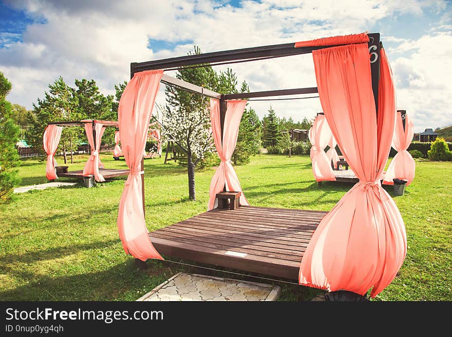 Summer wooden gazebo with a white cloth in the garden. living coral