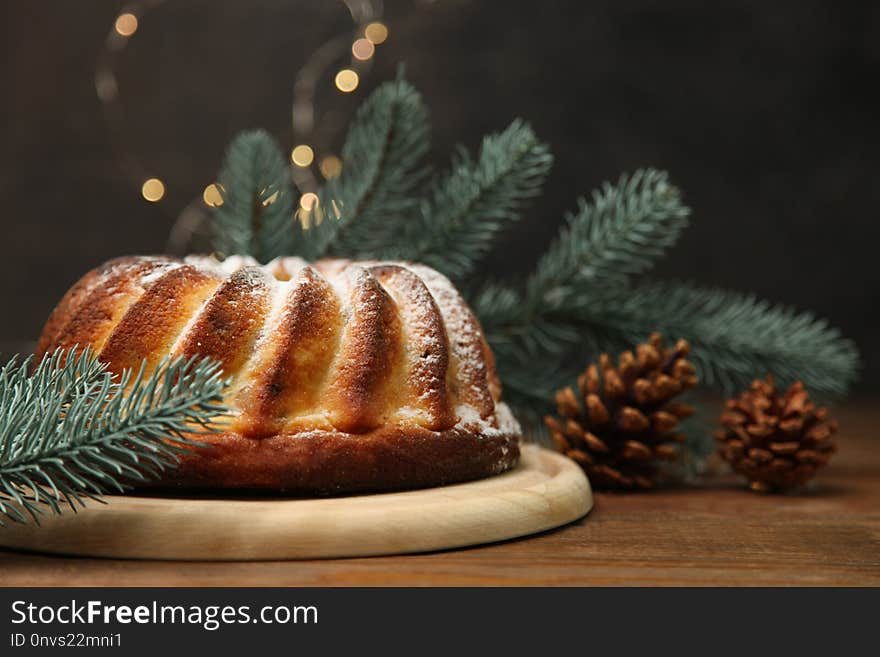 Baked cottage cheese cake on cutting board and branch fir with cones on wooden table on black background with yellow lights. Baked cottage cheese cake on cutting board and branch fir with cones on wooden table on black background with yellow lights