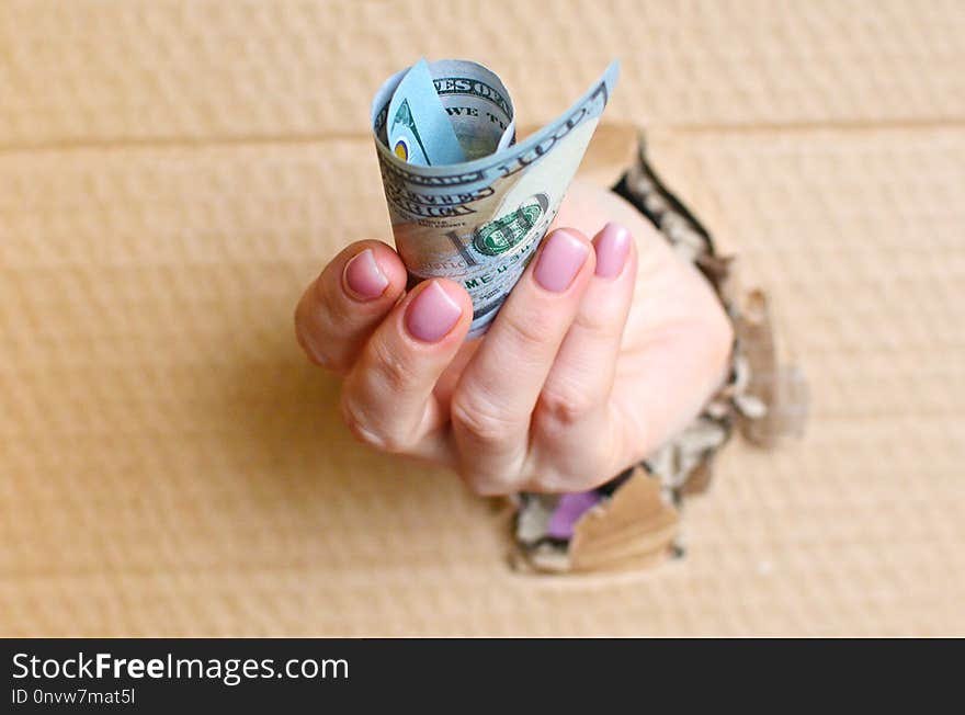 Bribe or payment concept. Giving hand with dollars through the hole.