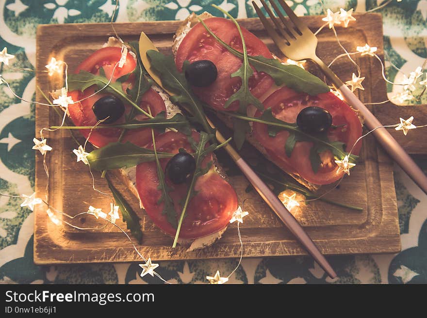 Healthy snack or Tomato, arugula, olives and creamy cheese on toast bread. Organic breakfast