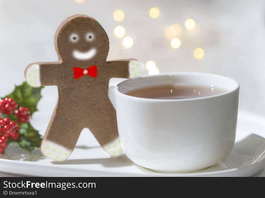 Gingerbreadman cookiee decorated for christmas and a cup of hot coffee for you on a joyful holy day. Xmas flower is on the left side of the plate. Macro photography