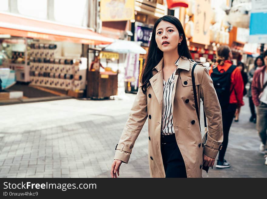 Beautiful woman in casual suit walking in dotonbori in osaka city japan. busy urban people lifestyle concept. young girl shopping alone outdoor on sunny day in summer business travel trip