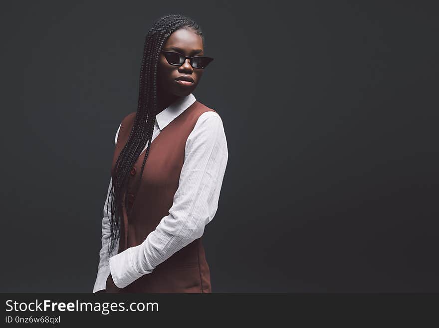 Stylish fashion young african woman in sunglasses gainst dark background