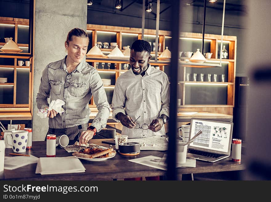 Delighted two males standing at their workplace