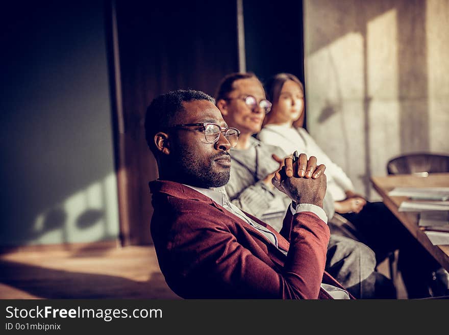 Being in all ears. Attentive international manager wearing stylish glasses while visiting training. Being in all ears. Attentive international manager wearing stylish glasses while visiting training