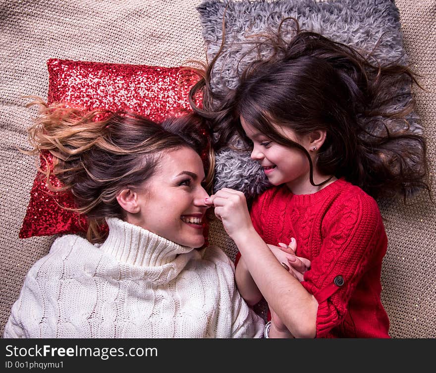 Loving daughter with sweaty hair is playing with her mother, lying on the pillows care, comfort, mother-worn-out, idyll, emotions