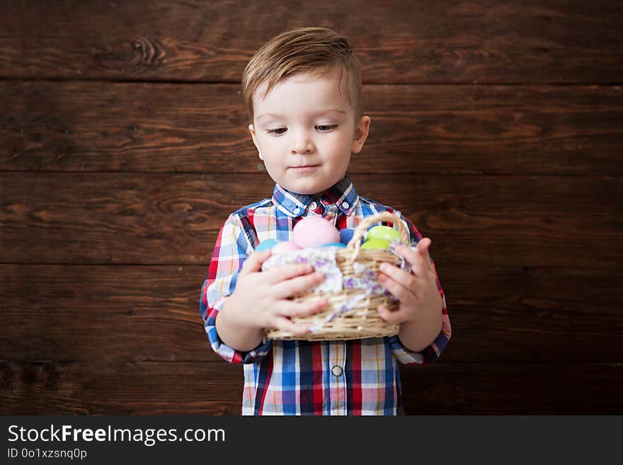 Happy Baby Boy With A Basket Of Eggs On Wooden Wall Background