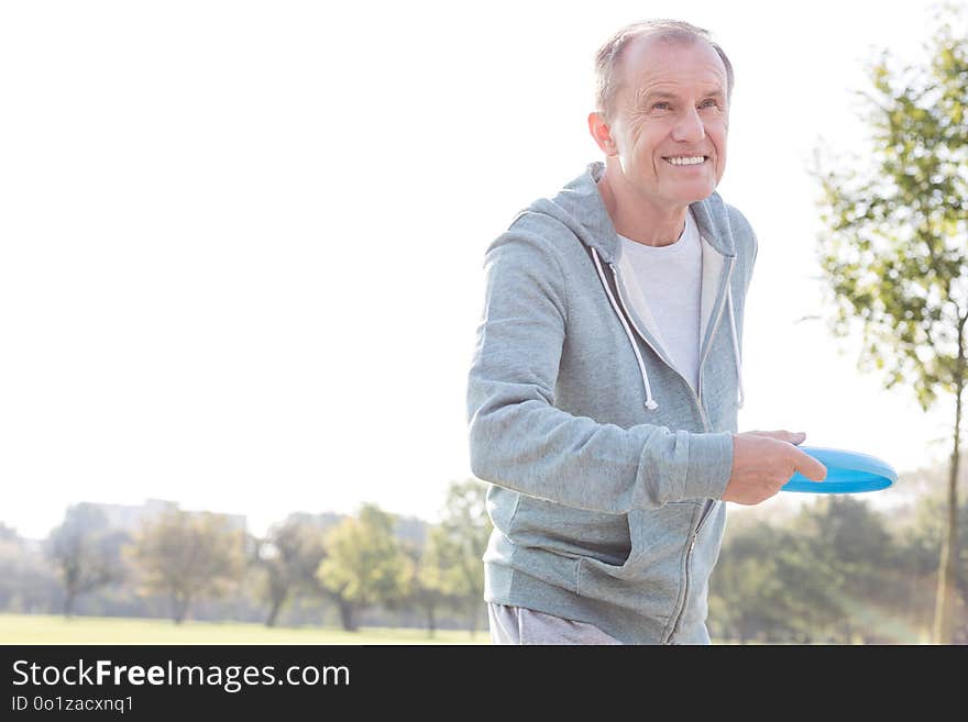 Smiling senior man throwing disc in park