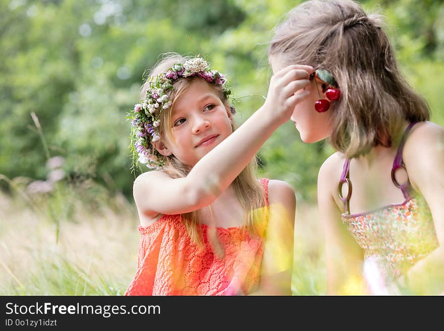 Cute girl holding cherry fruits on friend`s ear at par