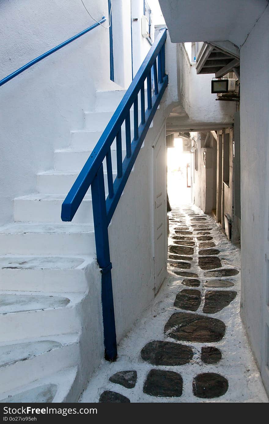 traditional narrow street in Mykonos with blue doors and white walls