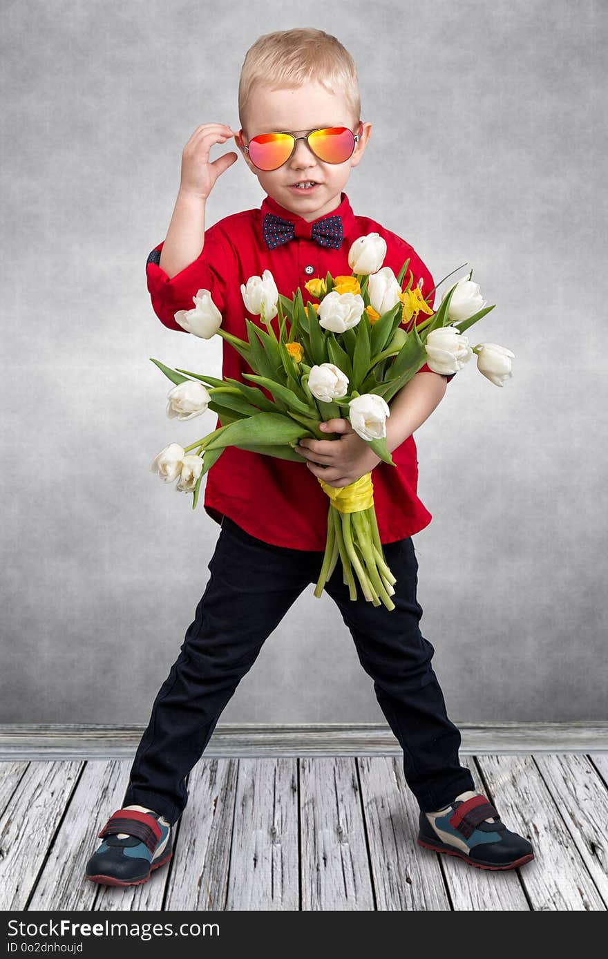 Stylish little boy holds a bouquet of spring tulips.Spring,holiday,children`s fashion.