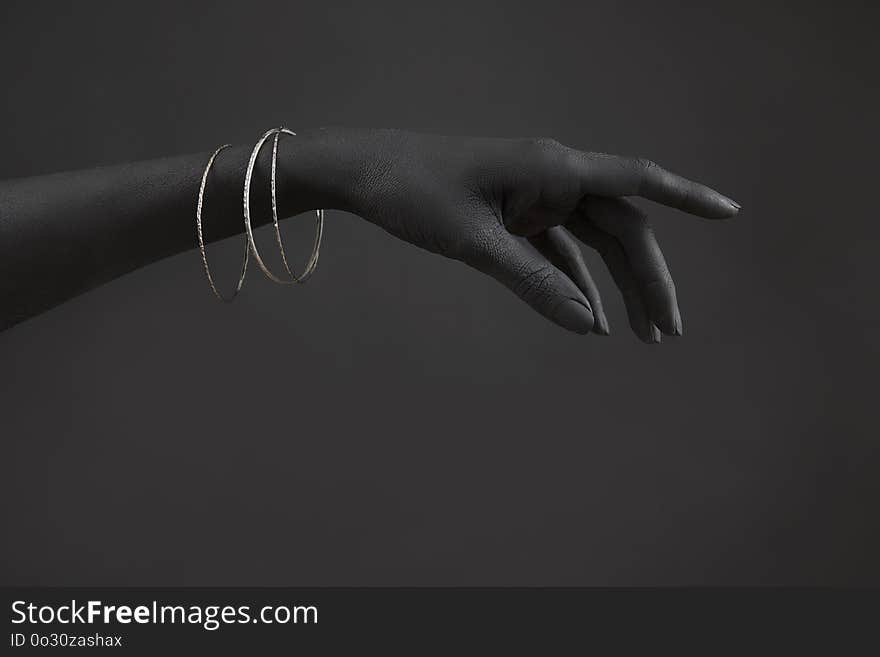 Black woman`s hand with Silver jewelry. Oriental Bracelets on a black painted hand. Silver Jewelry and luxury accessories on black background closeup. High Fashion art concept