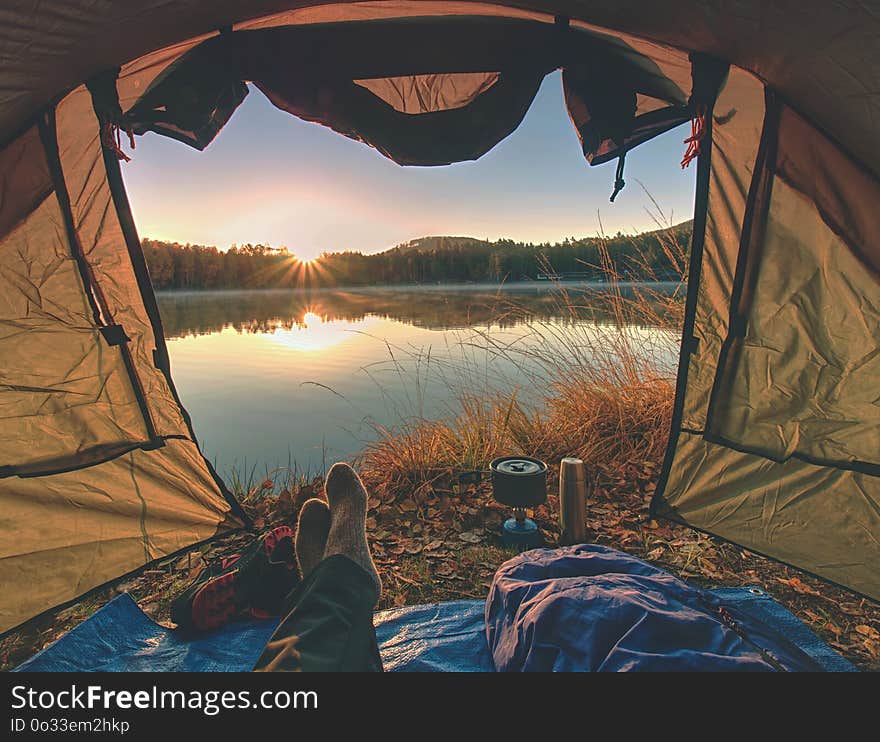 Couple legs rest in tent at lake. Hiker enjoy view outsid and e free hike vacation