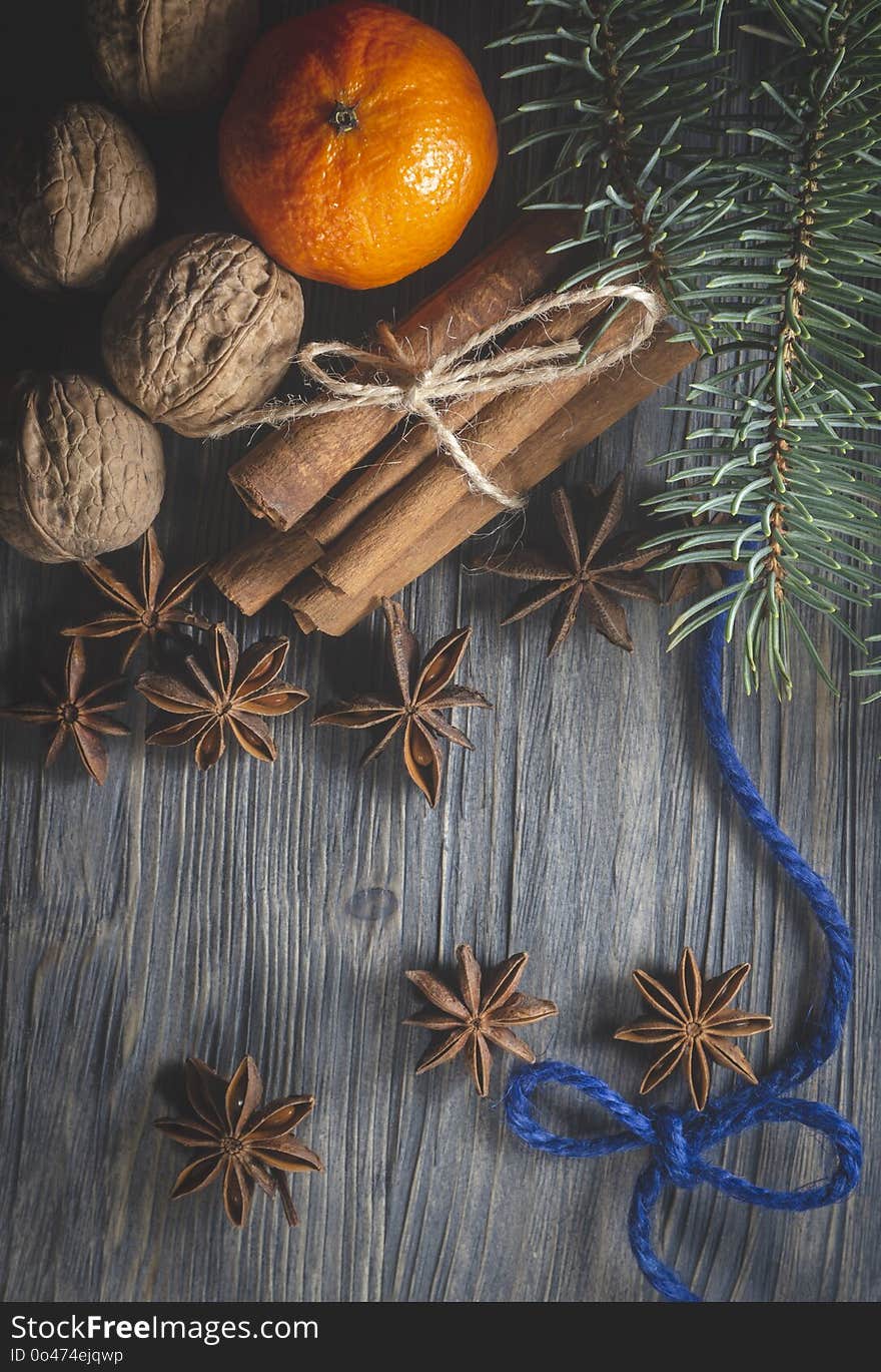 Star anise, bunch of cinnamon, blue thread and orange and next to pine branch, sitting on rustic wooden table surface background. Christmas decor, cosiness, warmth, mulled wine recipe concept. Star anise, bunch of cinnamon, blue thread and orange and next to pine branch, sitting on rustic wooden table surface background. Christmas decor, cosiness, warmth, mulled wine recipe concept